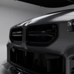 Close-up of carbon fibre front bumper grille on BMW G87 M2, showing dual intake and ASM badging
