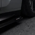 Straight close-up of carbon fibre side skirt running beneath grey BMW M4 G82 door line