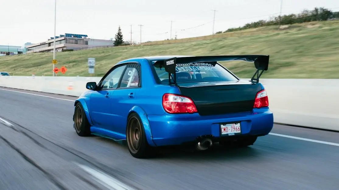 Blue Subaru STI with exhaust upgrades for turbos cruising on highway, showcasing dynamic motion.