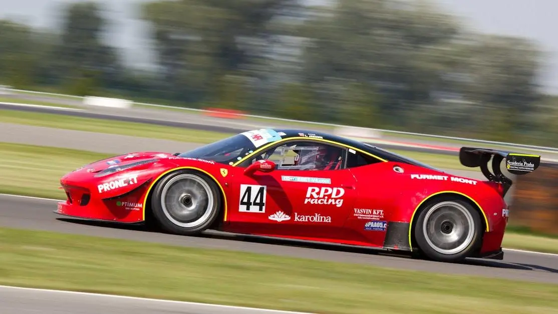 Red Race Car On Track In Daylight, Showcasing Best Tires For Performance.
