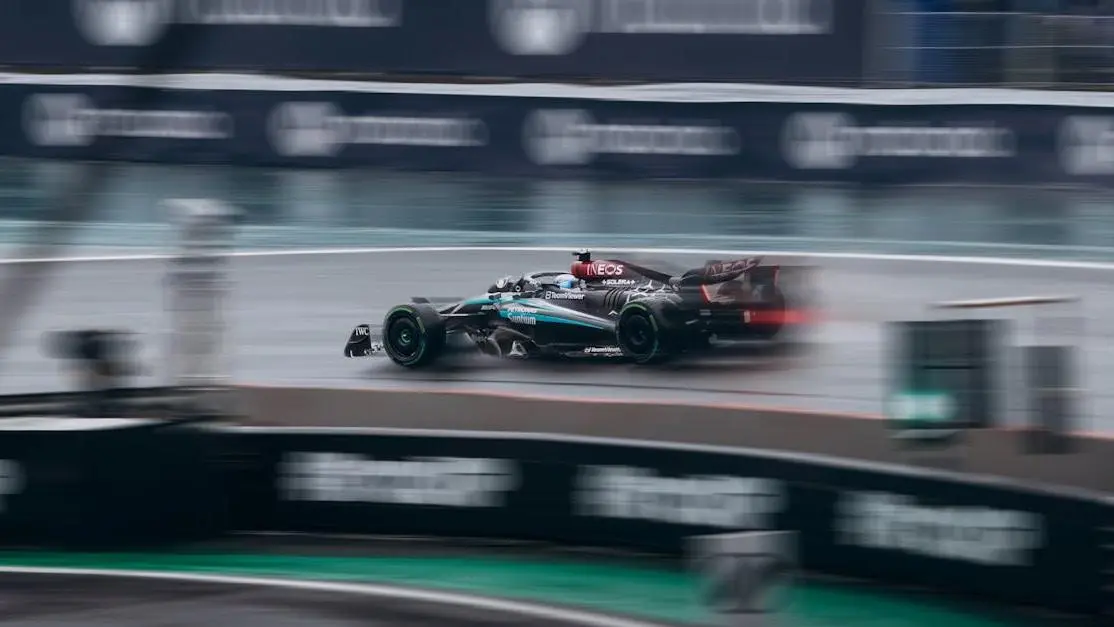 Race car showcasing downforce in car mods on a wet Formula 1 track.