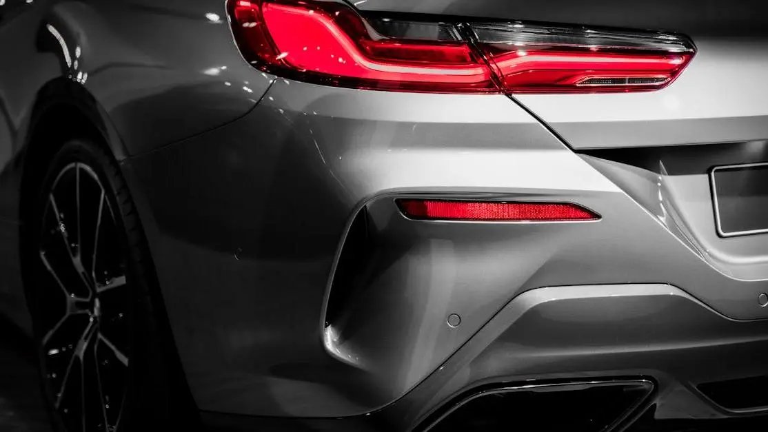 Aftermarket car exhaust on a sleek grey car’s rear with illuminated red brake light