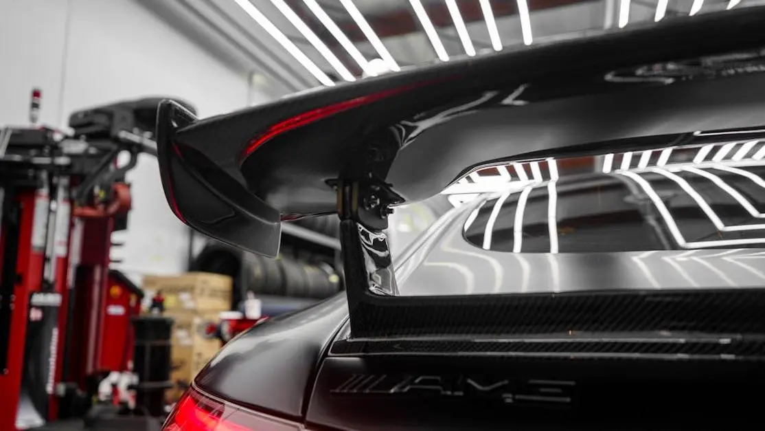 Sportscar spoiler in professional garage showcasing aftermarket replacement auto parts