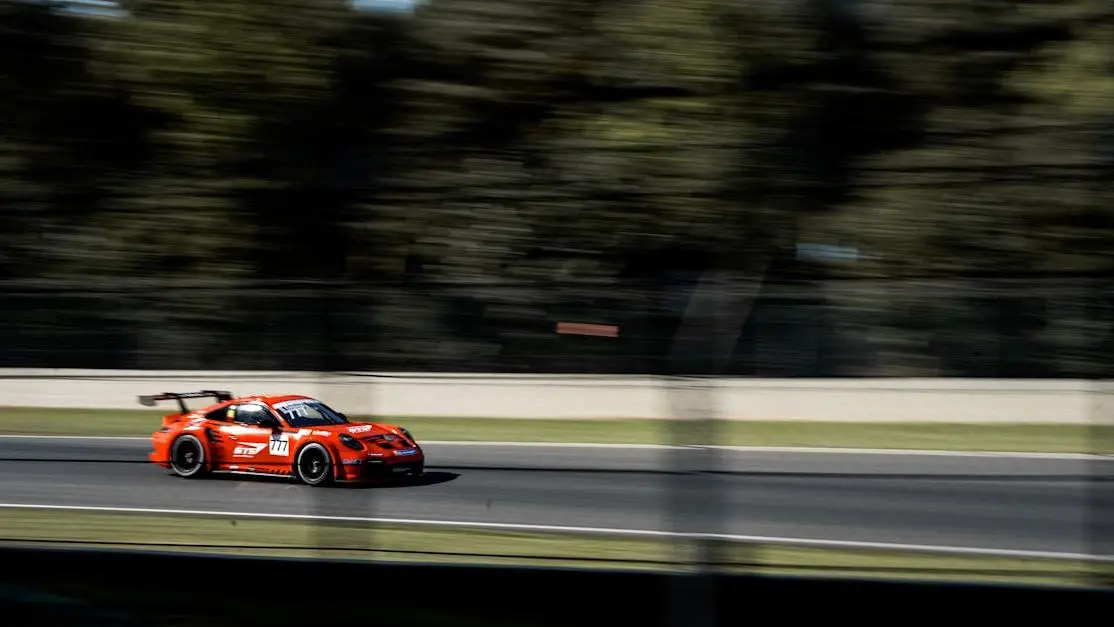 Red race car speeding at Circuit de Zolder, Belgium, highlighting performance race car parts