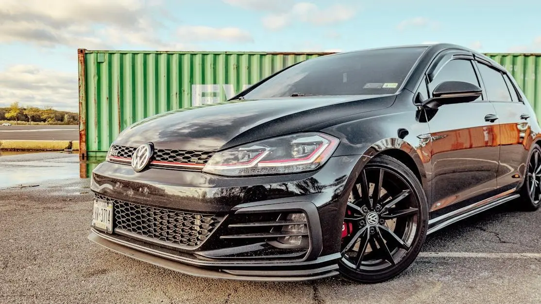 Black Volkswagen Golf 4 with sporty styling beside green freight container, showcasing golf 4 body kits